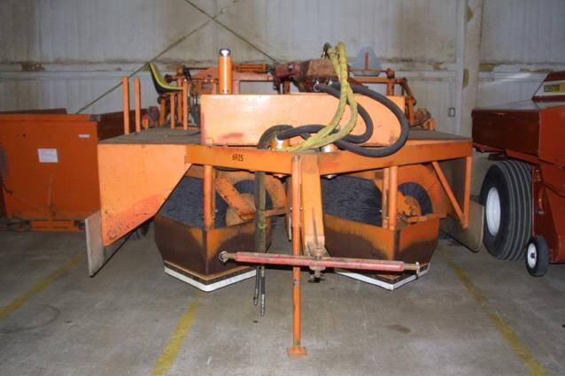 Photo showing machinery used to brush sawdust on top of stems.